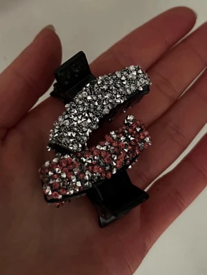  hårklämmor med diamanter 2 st för 100 kr! :) - 2 st för 100 kr! :) Två hårklämmor i svart plast dekorerade med gnistrande stenar, en i silver och en i rosa. Klämmorna har rektangulär form och är perfekta för att ge frisyren extra bling.  