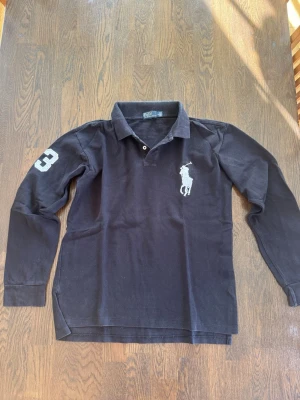 Ralph lauren långärmad piké  - Klassisk svart långärmad polotopp från Polo Ralph Lauren äkta såklart. Pappas gamla köpt i srilanka för ca 15 år sedan väldigt sällsynt och bra bevarad.