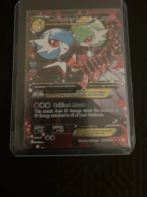 Pokémonkort Mega Gardevoir EX - Säljer ett Pokémonkort Mega Gardevoir EX med 210 HP. Kortet har färgerna blå, grön, röd och svart med holografisk effekt. Det är inplastat i ett skyddsfodral. Perfekt för samlare eller Pokémonfans.