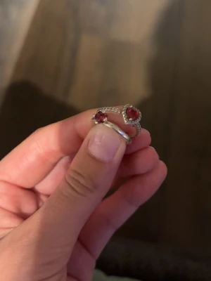 Silverring med hjärtformad röd sten - Ringen har en öppen design och är dekorerad med små gnistrande stenar längs ena sidan. Dem är sparsammt använda och jag säljer dem för att jag har svårt för ”ring-känslan”. Perfekt accessoar för att ge din stil lite extra glans. Det är äkta silver 925 och den förta ringen säljs inte längre och den andra kostar 800kr nypris. Jag säljer dem för 650 styck💕skriv privat för att köpa💕