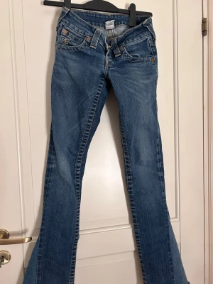 Blå bootcut jeans från True Religion - Blå långa bootcut true religion jeans, sytt dom till bootcut själv så det är inte perfekt längst ner på dom och lite trasig fick (se på bild) 
