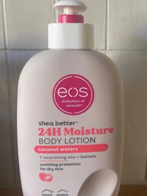 EOS 24H Moisture Body Lotion Coconut - Body lotion från EOS med doft av coconut waters. Innehåller sheasmör, sheaolja och sju närande oljor och smör. Ger silkeslen återfuktning i 24 timmar. Vegansk, parabenfri och passar känslig hud. Flaskan är ljusrosa med pump.