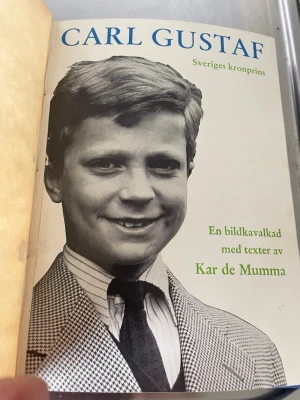 Carl Gustaf – En bildkavalkad - Boken 'Carl Gustaf – Sveriges kronprins' är en bildkavalkad med texter av Kar de Mumma. Innehåller svartvita fotografier och texter om Carl Gustaf. Omslaget är ljust med blå och grön text, och boken har klassisk inlaga i papper. Gammal men i nytt skick 