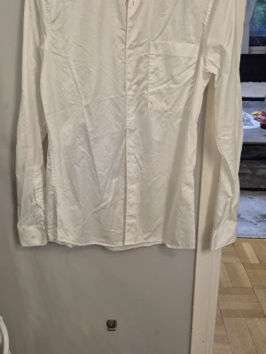 Vit henley-skjorta från Emilio - Snygg vit henley-skjorta från Emilio med lång ärm och bröstficka. Skjortan har knappar framtill och är tillverkad i mjuk bomull. Perfekt för en clean och stilren look.
