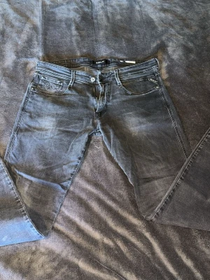 Replay anbass jeans  - Snygga svarta jeans från Replay med klassisk femficksmodell och raka ben. Jeansen har diskreta slitningar och detaljerade sömmar på bakfickorna. Perfekta för en avslappnad och trendig look. Passform anbass
