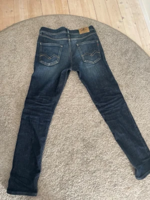 Blå jeans från Replay - Säljer ett par klassiska blå jeans från Replay med snygga bakfickor och kontrastsömmar. Jeansen har en normal passform och är tillverkade i slitstarkt denim. Perfekta till din vardagsstil!