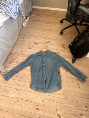 Ralph Lauren skjorta - Säljer denna jeans skjorta från Ralph Lauren i bra skick med en liten defekt på framsidan. 