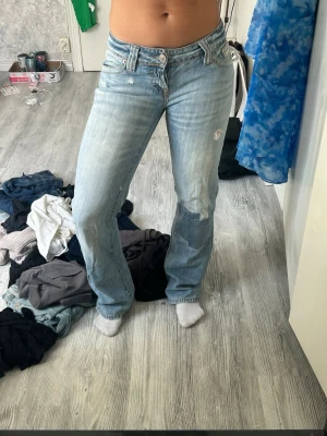 Lowwaist jeans från Zoul - Ljusblå jeans från Zoul med klassisk femficksdesign och lätt slitna detaljer på ben och bakficka. Jeansen har raka ben och normal midja, tillverkade i denim med en skön passform. Perfekt för dig som gillar en avslappnad och trendig look.