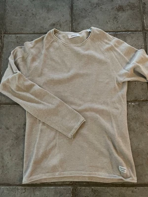 Beige långärmad tröja Jack & Jones - Snygg beige långärmad tröja från Jack & Jones. Tröjan har en enkel och stilren design med rund hals och diskret struktur i materialet. Perfekt för en avslappnad look och lätt att matcha med andra plagg.