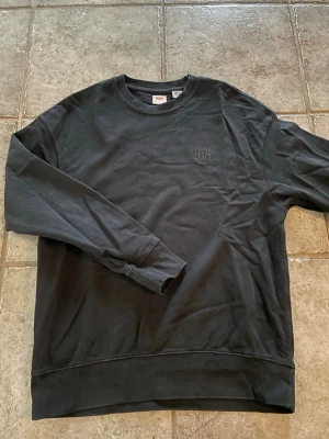 Svart sweatshirt från Levi's - Svart sweatshirt från Levi's i relaxed fit. Tröjan har rund halsringning, långa ärmar och diskret broderad logga på bröstet. Perfekt för en chill och stilren look.