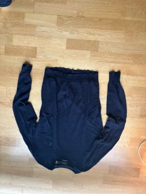 Mörkblå tröja från Ralph Lauren - Mörkblå långärmad merinoull tröja från Ralph Lauren med rund halsringning och diskret broderad logga på bröstet. Tröjan är tunnstickad och har ribbade muddar vid ärmslut och nederkant. Perfekt för en stilren och klassisk look. Storlek M men passar S