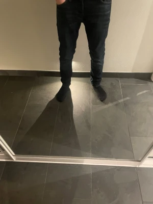 Mörkblå slim fit jeans - Snygga mörkblå slim fit jeans med klassiska fem fickor och kontrastsömmar. Jeansen har en något tvättad look och smal passform. Perfekta för en trendig stil.
