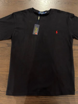 Black t-shirt - A plain black t-shirt with a red logo in the size M