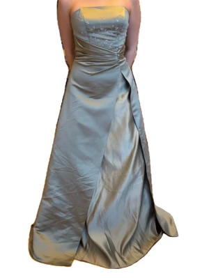 Ljusgrön axelbandslös balklänning - Elegant axelbandslös långklänning i ljusgrönt satinliknande material med broderier upptill och draperad detalj i midjan. Klänningen har en puffig look och är perfekt för bal eller festliga tillfällen. Skriv om ni har några frågor! 🥰