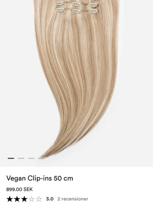 Blonda syntetiska clip-in löshår 50 cm - Snygga blonda clip-in extensions i syntetiskt material, 50 cm långa och med rak hårstruktur. Perfekta för dig som vill ha extra volym och längd på ett enkelt sätt. Fästs med klassiska clips och ger ett naturligt resultat.