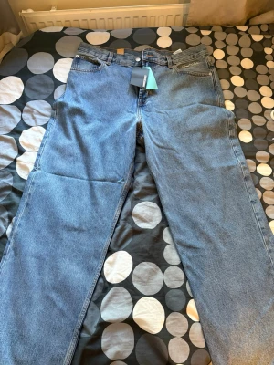 Blå raka jeans från Sweet SKTBS - Snygga blå jeans med rak och lite oversized passform och klassisk femficksdesign. Jeansen har lite stor midja och är tillverkade i denim. Etiketten är fortfarande på, inte använts. Originalpris: 699kr