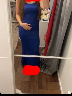 Blå långklänning med smala axelband - Snygg blå långklänning med smala axelband och figurnära passform. Klänningen har en enkel, elegant design och är perfekt för dig som vill ha en stilren look. Passar till många olika tillfällen och är lätt att matcha med accessoarer.