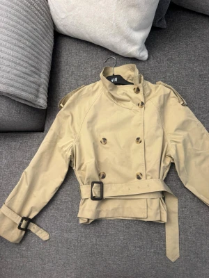 Beige trenchcoat  - Stilren beige trenchcoat som är använd men i bra skick. Osäker på vart den är ifrån därav pris! Storlek xs!