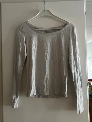 Ljusgrå långärmad topp - En enkel och stilren ljusgrå långärmad topp med rund halsringning. Tillverkad i mjukt bomullsmaterial som känns skönt mot huden. Perfekt att matcha med jeans eller kjol för en clean look.