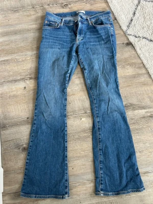 Blå bootcut jeans  - Säljer ett par klassiska blå bootcut jeans med normal midja eller lite lågmidjade. Jeansen har en snygg tvätt och utsvängda ben.