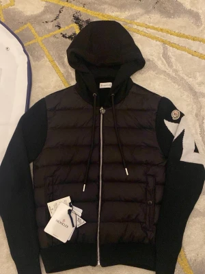 Mocnler cardigan M text  - Snygg svart hoodie från Moncler med vadderad front och stickade ärmar. Kommer med originala förpackning inga skador eller fläck nästan som helt ny, kan gå ner i pris vid snabb affär! ”Scan funkar”
