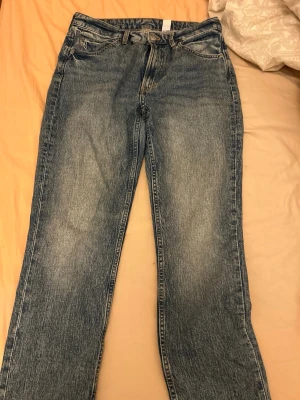Blå slim straight jeans high waist - Ett par blå slim straight jeans med hög midja och regular fit. Klassisk femficksmodell i tvättad denim med snygga slitningar och raka ben. Perfekta för en avslappnad och trendig look.