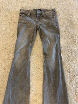 True religion  - Säljer ett par grå bootcut jeans med snygga fickdetaljer bak och vita sömmar. Storlek 26. Bara höra av er vid frågor 🩷