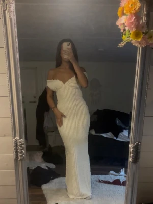 Vit klänning - Säljer en vit långklänning med offshoulder-design. Klänningen har en figurnära passform och knytning i ryggen för extra detalj. Perfekt för balen exempelvis.😊