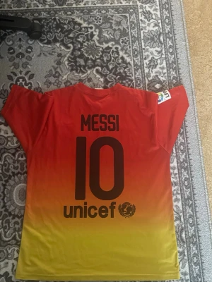 Barcelona Messi matchtröja röd/gul - Säljer en Barcelona matchtröja med Messi 10 på ryggen. Tröjan har en snygg röd till gul färgövergång, klubbmärke på bröstet och Qatar Foundation-tryck framtill. Korta ärmar och rund hals. Perfekt för dig som älskar fotboll och Messi.