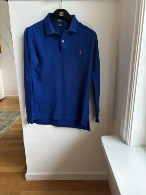 Blå långärmad pikétröja Polo Ralph Lauren - Klassisk blå Ralph Lauren pikétröja i st M 12-14år för endast 125kr. Nypris 1200kr