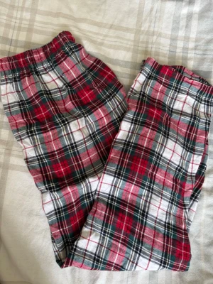 Röd-rutiga pyjamasbyxor 2XL - Mysiga pyjamasbyxor i röd, vit och svart rutigt mönster från märket C. Byxorna har resår i midjan och är tillverkade i mjukt, vävt tyg som passar perfekt för chillkvällar hemma. Klassisk flanell-look som aldrig går ur tiden.