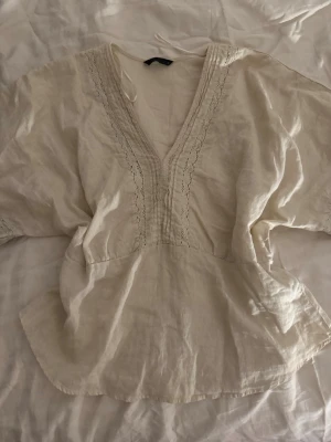 Krämvit blus med v-ringning - Säljer en väldigt somrig och fin blus i färgen beige. Köpte den för inte så länge sedan och den är i ett väldigt bra skick!