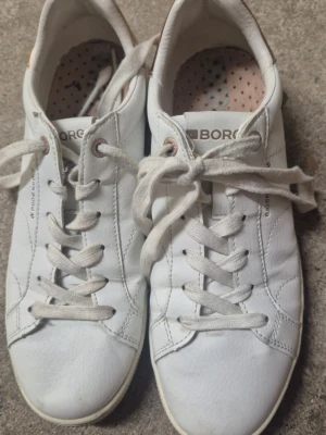 Vita låga sneakers från Björn Borg - Snygga vita sneakers från Björn Borg med klassisk design och lågt skaft. Skorna har vita snören, diskreta sömmar och detaljer samt en bekväm innersula med prickigt mönster. Perfekta för en clean och stilren look. Skorna är endast använd någon enstaka gång, har legat i källaren en längre tid så kan vara lite dammiga bara.
