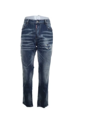 Mörkblå distressed jeans med raka ben - Snygga mörkblå jeans med raka ben och slitna detaljer, inklusive en reva på låret och stänk-effekter över hela tyget. Jeansen har klassisk femficksdesign och knappgylf. Perfekta för en cool och avslappnad stil.