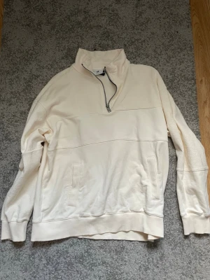 Vit halfzip sweatshirt från H&M - Stilren vit sweatshirt med halv dragkedja från H&M. Tröjan har hög krage, ribbade muddar och två fickor framtill.