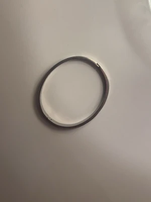 Silverfärgat stålarmband med detaljer - Snyggt armband i silverfärgat stål med rund form och ingraverade skruvliknande detaljer runt om. Armbandet har en stilren och modern look som passar till många olika outfits. Perfekt accessoar för dig som gillar minimalistisk design.