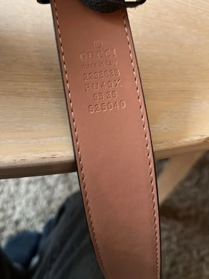 Svart Gucci skärp med guldspänne - Snyggt svart Gucci bälte med klassiskt GG-mönster och stort guldigt GG-spänne. Bältet är gjort i skinn och har en lyxig känsla med detaljer i beige på insidan. Perfekt accessoar för att lyfta vilken outfit som helst.