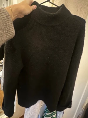 Svart stickad halvpolotröja - Mysig svart stickad polotröja med lång ärm och uppvikta muddar. Tröjan har en hög krage och är gjord i ett mjukt, grovstickat material som passar perfekt när det är kallt ute. Oversized i storleken ❤️okej/bra skick