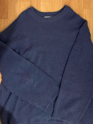 Mörkblå stickad tröja 157 - Mysig mörkblå stickad tröja från 157 med rund halsringning och långa ärmar. Tröjan har en enkel och klassisk design med ribbstickade muddar vid ärmslut och nederkant. Kannor använd ❣️