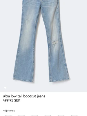 Ljusblå bootcut jeans med slitningar - Säljer ett par ljusblå bootcut jeans med låg midja och slitna detaljer på benen. Jeansen var en julklapp men sitter lika kort i min smak (är 181) och de är typ 3 cm för korta. Helt oanvända men tyvärr ej prislapp kvar, enbart testade.