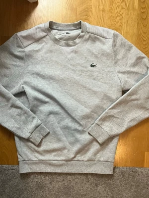 Lacoste Crewneck  - Riktigt stilig och bekväm Lacoste Crewneck, perfekt nu till våren samt sommar då den andas väldigt bra och man blir inte så jätte varm i den. Helt perfekt skick och storlek S.