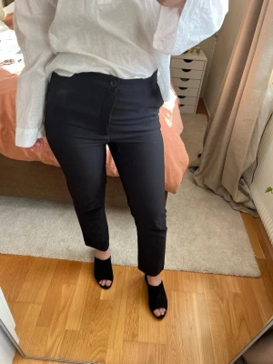 Svarta kostymbyxor - Svarta kostymbyxor med hög midja, ankellängd. Fickor framtill, storlek 36 Innebenlängd 70