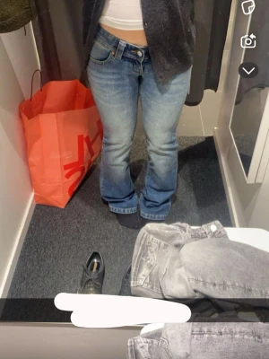 Blå bootcut jeans med låg midja - Snygga blå bootcut jeans med låg midja och klassisk femficksdesign. Jeansen har en lätt tvättad look och raka ben som går ut lite nedtill. Perfekta för en avslappnad och trendig stil.