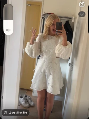 Vit kort klänning med puffärmar - Säljer nu min fina studentklänning från By Malina🥰i hopp om att den får användas på nytt!. Klänningen har en rund halsringning och markerad midja, vilket ger en feminin siluett. Perfekt för student eller sommarens festligheter. På bild nummer 6 visas knapparna i bak på klänningen där en av knapparna hänger lite löst, har inte orkat fixa det men det behövs bara sys fast lite bättre. Klänningen har kemtvättats och är annars endast använd 1 gång 🤩Budgivning startar på 2000 kr! 