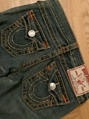 Lågmidjade True religion jeans - Supersnygga lågmidjade bootcut true religion jeans. Lite små slitningar som syns på bilderna men inget man tänker på! De är rätt korta i modellen så skulle rekommendera för någon som är lite kortare😊. Skriv gärna vid funderingar!
