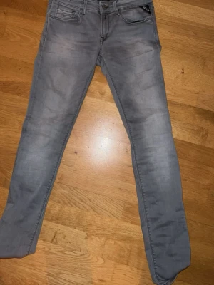 Grå repost jeans w27 - Säljer ett par grå slim fit jeans från Replay med klassisk femficksdesign och dragkedjegylf. Jeansen har en snygg tvättad look och smal passform som sitter tajt längs benen. Perfekta för en trendig och avslappnad stil.