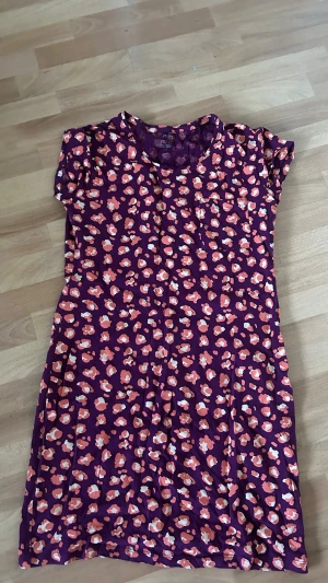 Lila kortärmad sovplagg Esmara - Söt lila kortärmad klänning från Esmara med färgglatt blommigt mönster i rosa, orange och vitt. Klänningen är i mjukt material och har en avslappnad passform, Perfket sovplagg 