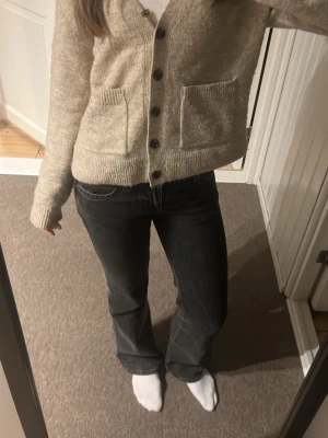 Svarta bootcut jeans med fickdetalj - Säljer ett par svarta lågmodjade bootcut jeans ifrån gina Tricot med snygga sömmar och en knappdetalj på bakfickan. De är i perfekt skick förfutom små slitningar längst ner, knappt använda 💕💕