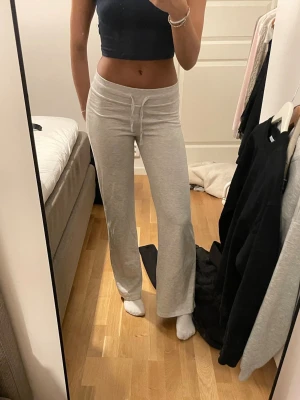 Gråa vida mjukisbyxor från Ginatricot - Säljer ett par ljusgrå mjukisbyxor med vida ben från Ginatricot. Byxorna har en relaxed fit och är tillverkade i mjukt sweatshirtmaterial. Inga synliga loggor eller märken. Har en liten fläck.