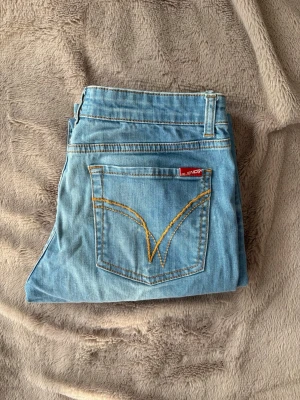 Vintage - PRIS GÅR ATT DISKUTERA. Snygga ljusblå vintage jeans från Blend med klassisk femficksdesign och gul kontrastsöm på bakfickan. Jeansen har rak passform och är tillverkade i denim med en röd Blend-logga på bakfickan. Perfekta för en avslappnad stil. Köpta mellan 1985-2005 så därav går dom inte längre att få tag på💗Storlek 29